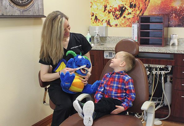 Dr. Ashley Ramsey showing a pediatric patient how to brush his teeth using a stuff animal